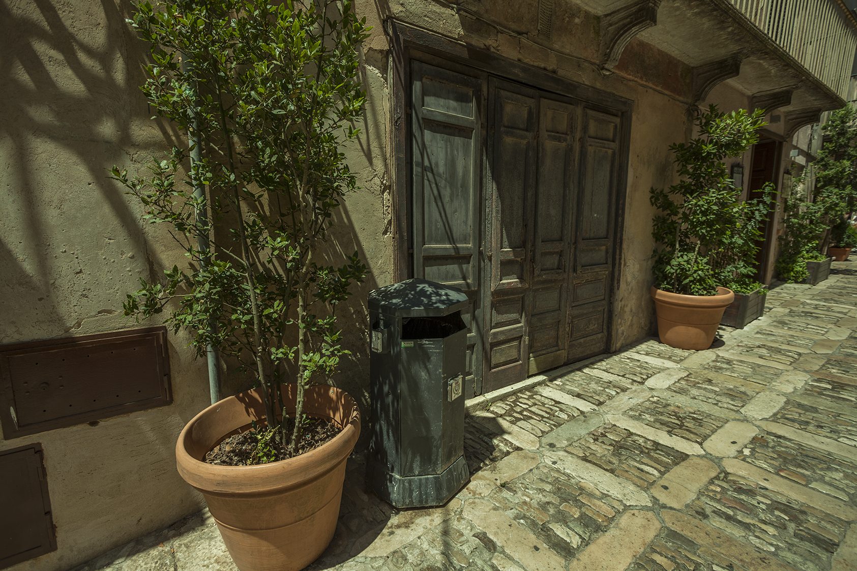 Eine enge Gasse in Erice mit poliertem Steinpflaster und einem Madonnenschrein.